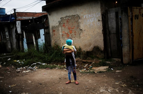 A girl holds her brother at the entrance of their house at a favela in Rio de Janeiro. (Credit Image: © Nacho Doce/Reuters via ZUMA Press)