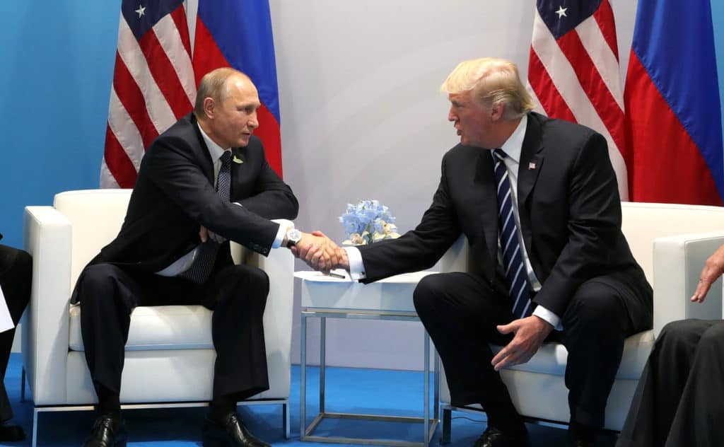 Donald Trump and Vladimir Putin shake hands.