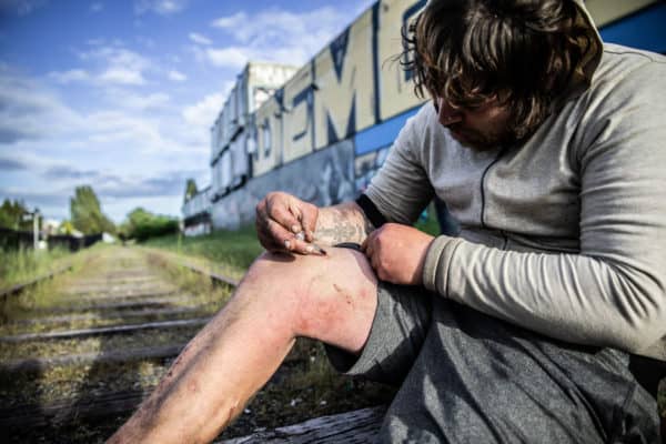 A heroin addict shooting up into his leg