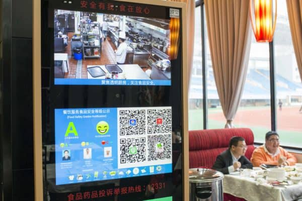 Shanghai, China – Diners eat lunch near a restaurant ‘sincerity display’ that provide video feeds from kitchens, health ratings and other information. Such displays are part of a “social credit” system. (Credit Image: © Dave Tacon / ZUMA Wire)