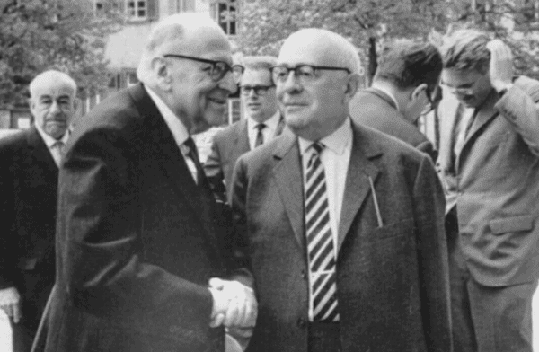 Max Horkheimer (L) and Theodore Adorno (R) shaking hands in 1964. Both were important “Frankfurt School” intellectuals, and considered the godfathers of critical theory. (Credit Image: Jjshapiro via Wikimedia)