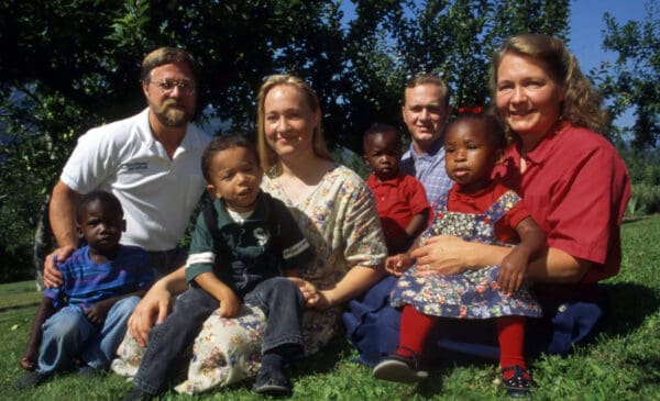 1996 年，前全国有色人种协进会领导人雷切尔·多莱扎尔和她的家人在蒙大拿州特洛伊市。身着白色花朵连衣裙的多莱扎尔（左二）在她的父母拉里·多莱扎尔（左）和鲁坦·多莱扎尔（右）透露后辞去斯波坎全国有色人种协进会主席的职务她是白人冒充黑人。 照片中还有她的兄弟 Joshua Dolezal 和家人收养的四个孩子。 （图片来源：© Kurt Wilson / Missoulian/ZUMAPRESS.com）