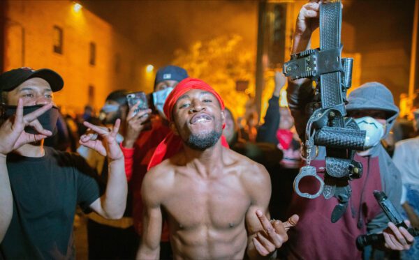 As the Minneapolis 3rd Police Precinct burns behind him, a protester and his friend proudly hold up a police belt during a riot over the killing of George Floyd. (Credit Image: © Chris Juhn/ZUMA Wire)